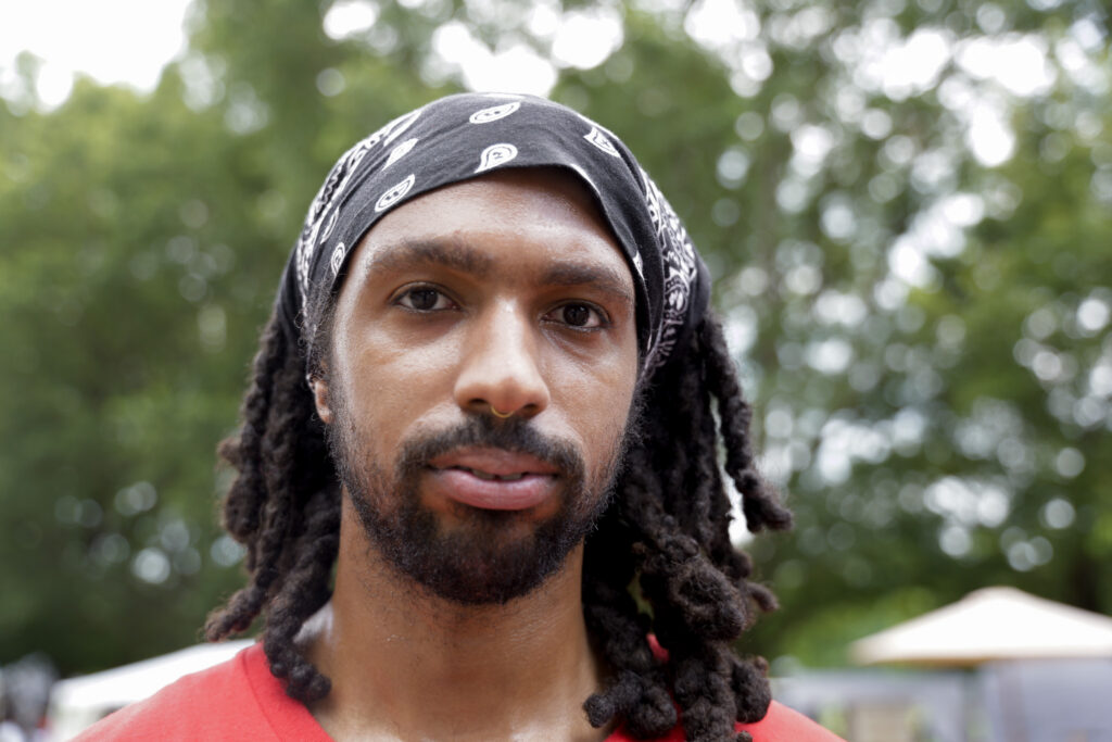 Michael Williams wears a black bandana and red shirt while posing for a portrait at Piedmont Park.